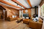 Experience rustic charm in this cozy living room, featuring warm wood paneling and exposed beams.