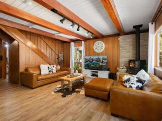 Experience rustic charm in this cozy living room, featuring warm wood paneling and exposed beams.