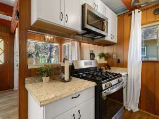 This charming kitchen features a stainless steel gas range and microwave, complemented by white cabinetry and granite countertops.