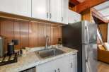 Discover this charming kitchen featuring a sleek stainless steel sink and faucet, complemented by warm wood paneling and modern white cabinetry.