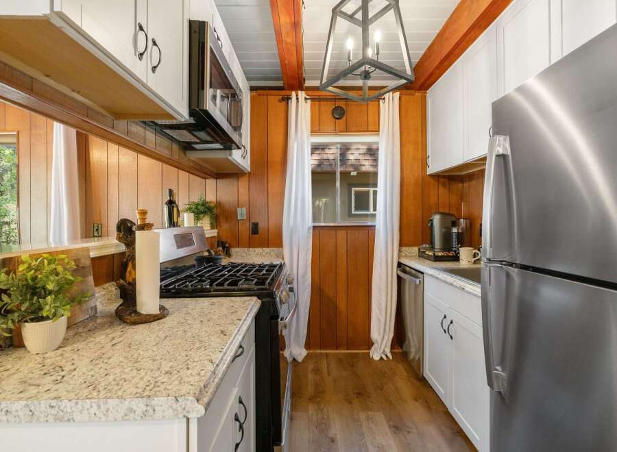 This charming kitchen features warm wood paneling and crisp white cabinetry, creating a cozy yet modern atmosphere.