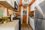This charming kitchen features warm wood paneling and crisp white cabinetry, creating a cozy yet modern atmosphere.