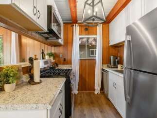 This charming kitchen features warm wood paneling and crisp white cabinetry, creating a cozy yet modern atmosphere.