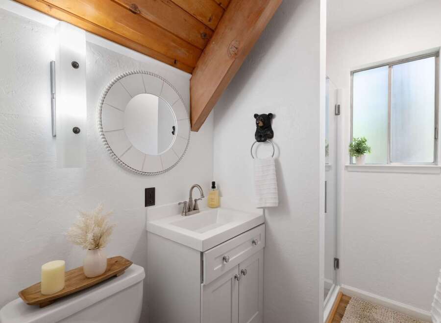 Charming bathroom featuring a white vanity with silver knobs, a round beaded mirror, and a unique black bear towel ring.