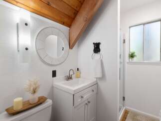 Charming bathroom featuring a white vanity with silver knobs, a round beaded mirror, and a unique black bear towel ring.