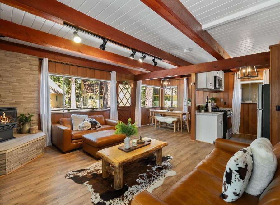 Experience rustic charm in this cozy cabin living space, featuring a warm wood-paneled interior and exposed wooden beams.