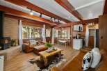 Experience rustic charm in this cozy cabin living space, featuring a warm wood-paneled interior and exposed wooden beams.