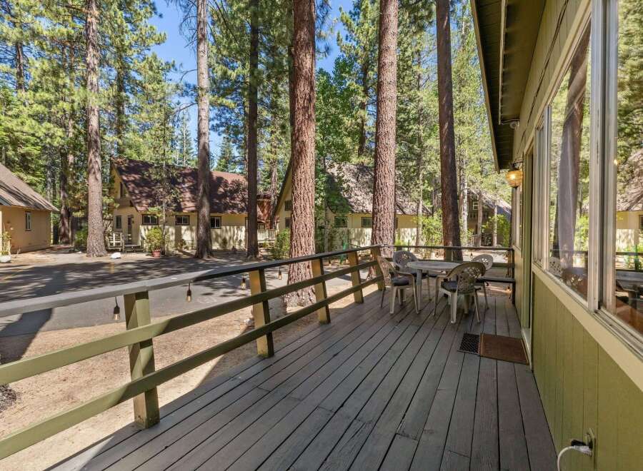 Enjoy outdoor living on this charming wooden deck, perfect for morning coffee or evening relaxation amidst towering pine trees.