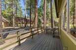 Enjoy outdoor living on this charming wooden deck, perfect for morning coffee or evening relaxation amidst towering pine trees.