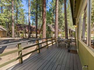 Enjoy outdoor living on this charming wooden deck, perfect for morning coffee or evening relaxation amidst towering pine trees.