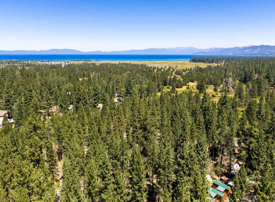Nestled amidst a dense forest of mature pine trees, this property offers a serene retreat with stunning views of a distant lake and mountains.