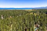 Nestled amidst a dense forest of mature pine trees, this property offers a serene retreat with stunning views of a distant lake and mountains.