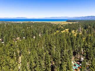 Nestled amidst a dense forest of mature pine trees, this property offers a serene retreat with stunning views of a distant lake and mountains.