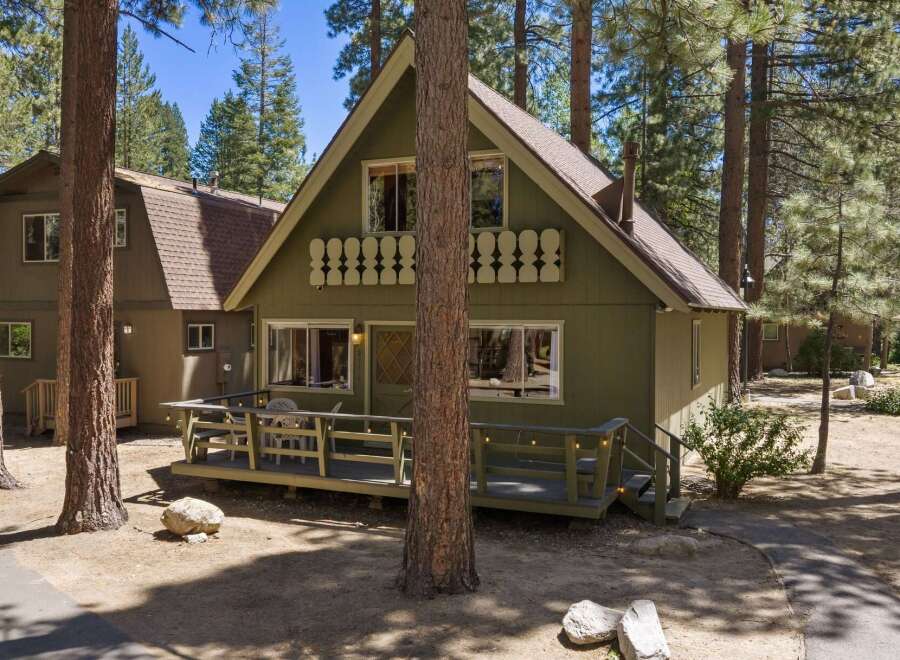Charming A-frame cabin nestled among tall pine trees, offering a serene mountain getaway.