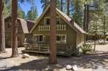 Charming A-frame cabin nestled among tall pine trees, offering a serene mountain getaway.
