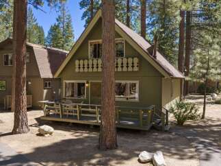 Charming A-frame cabin nestled among tall pine trees, offering a serene mountain getaway.