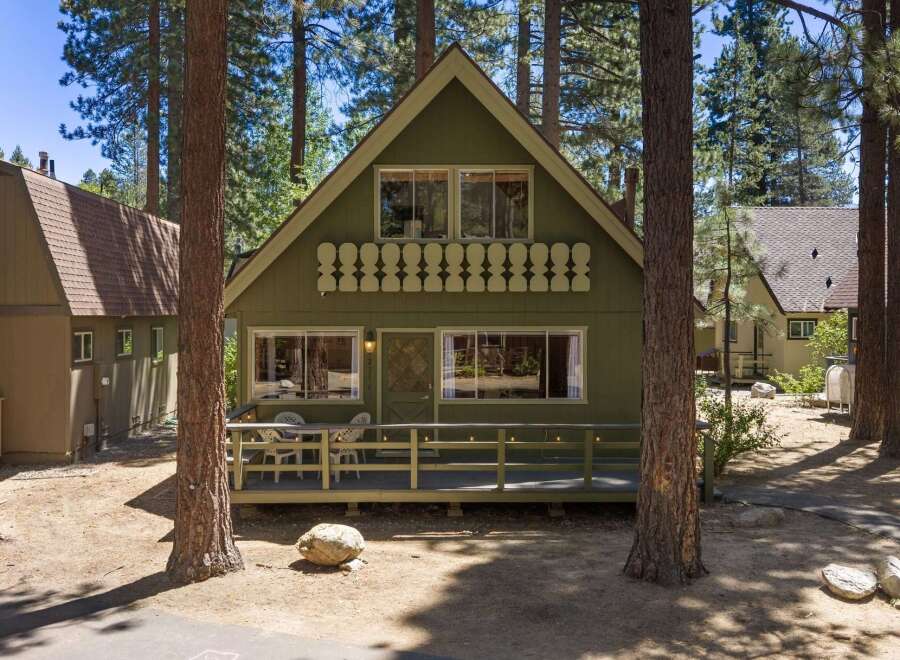 Charming A-frame cabin nestled among tall pine trees, offering a serene mountain retreat.