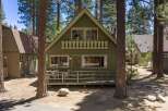 Charming A-frame cabin nestled among tall pine trees, offering a serene mountain retreat.