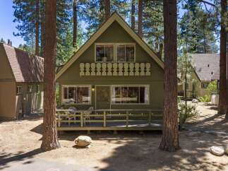 Charming A-frame cabin nestled among tall pine trees, offering a serene mountain retreat.