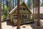 Nestled amongst tall pine trees, this charming green cabin offers a serene retreat.