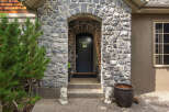 This charming home features a grand stone entryway with an arched doorway leading to a dark wooden door.