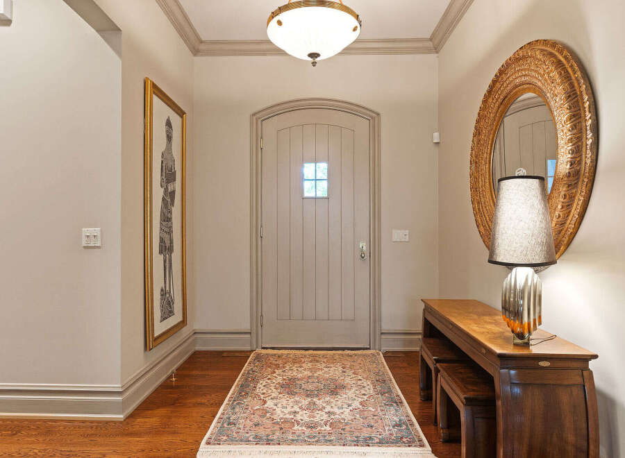 Step into a welcoming entryway featuring a charming arched door and a beautiful Persian rug.