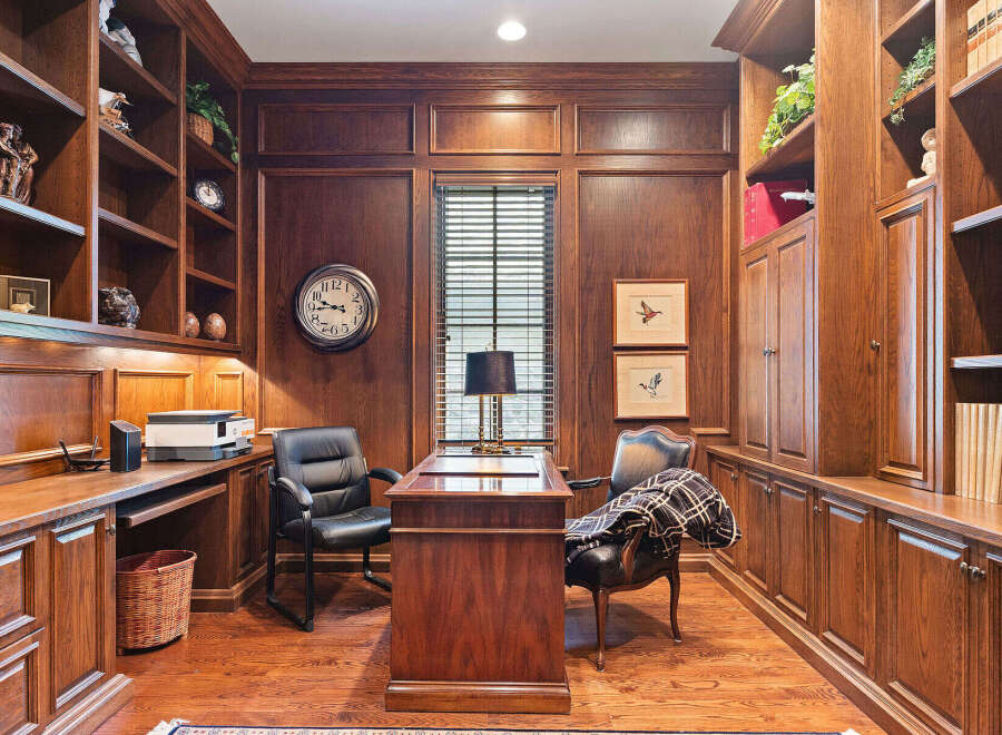 Step into this elegant home office, featuring rich mahogany built-in bookshelves and cabinetry that exude timeless sophistication.