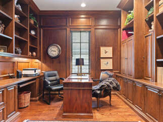 Step into this elegant home office, featuring rich mahogany built-in bookshelves and cabinetry that exude timeless sophistication.
