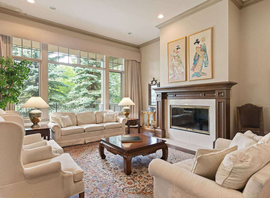 This elegant living room features a grand fireplace with intricate wood detailing and a marble surround, perfect for cozy evenings.