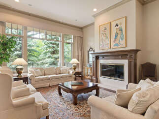 This elegant living room features a grand fireplace with intricate wood detailing and a marble surround, perfect for cozy evenings.