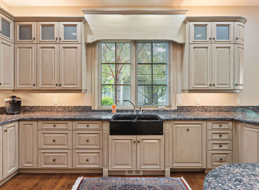 This spacious kitchen boasts custom cream-colored cabinetry with glass-paneled upper cabinets and intricate detailing.