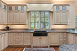 This spacious kitchen boasts custom cream-colored cabinetry with glass-paneled upper cabinets and intricate detailing.