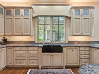 This spacious kitchen boasts custom cream-colored cabinetry with glass-paneled upper cabinets and intricate detailing.