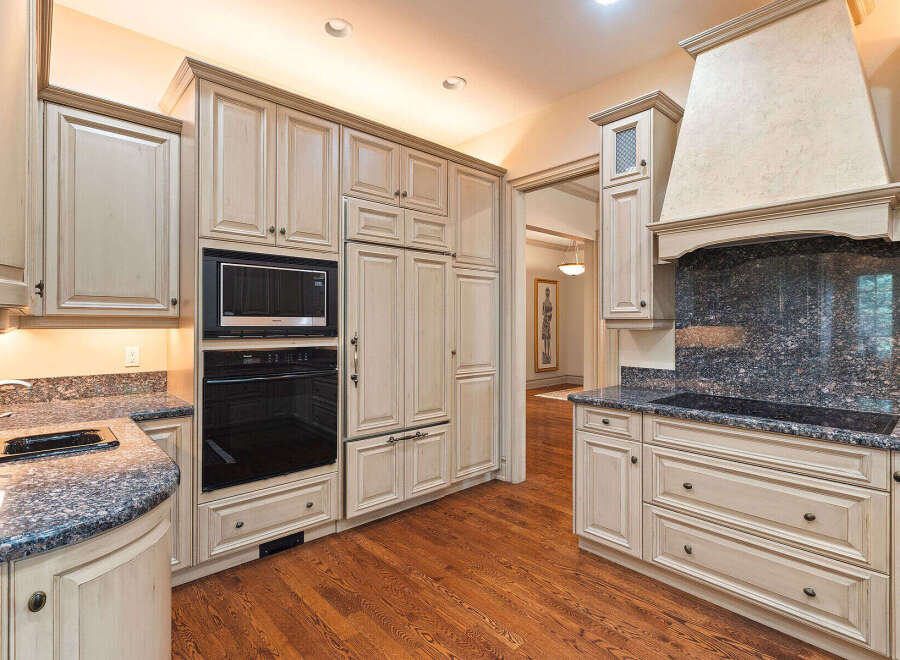Experience luxury in this stunning kitchen featuring custom cream-colored cabinetry and a built-in oven and microwave.