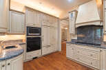 Experience luxury in this stunning kitchen featuring custom cream-colored cabinetry and a built-in oven and microwave.