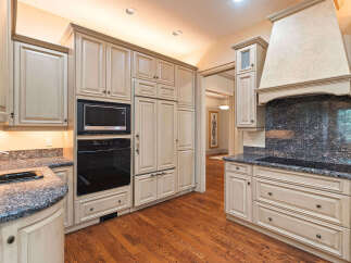 Experience luxury in this stunning kitchen featuring custom cream-colored cabinetry and a built-in oven and microwave.