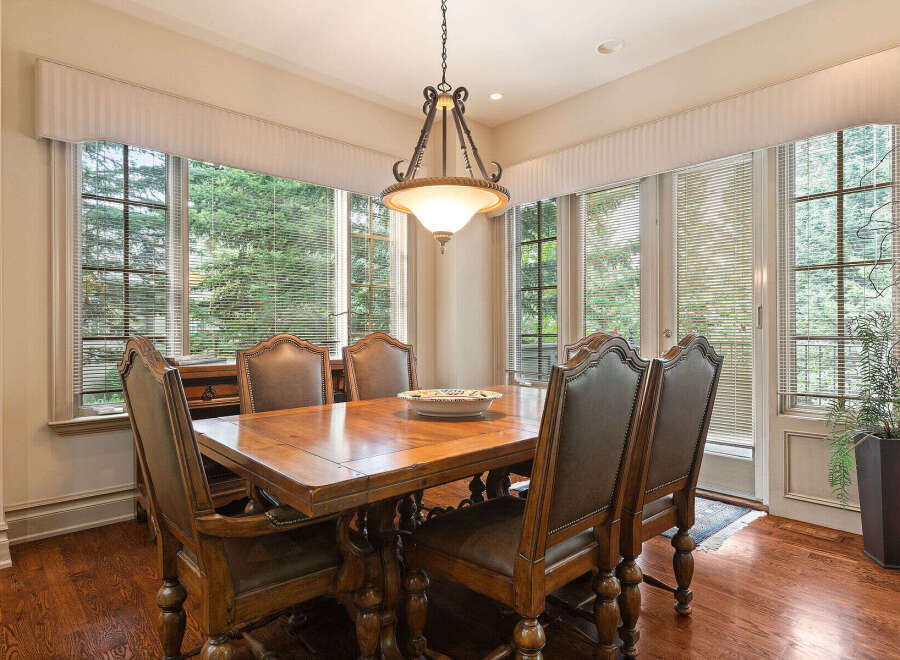 This elegant dining room features a large wooden table surrounded by plush leather chairs, perfect for hosting memorable meals.