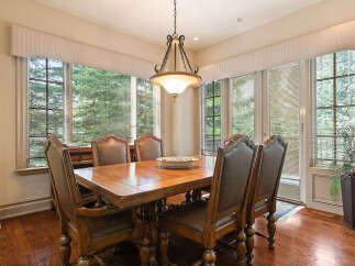 This elegant dining room features a large wooden table surrounded by plush leather chairs, perfect for hosting memorable meals.