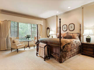 Experience luxurious comfort in this elegant bedroom, featuring a grand four-poster bed adorned with plush bedding and decorative pillows.
