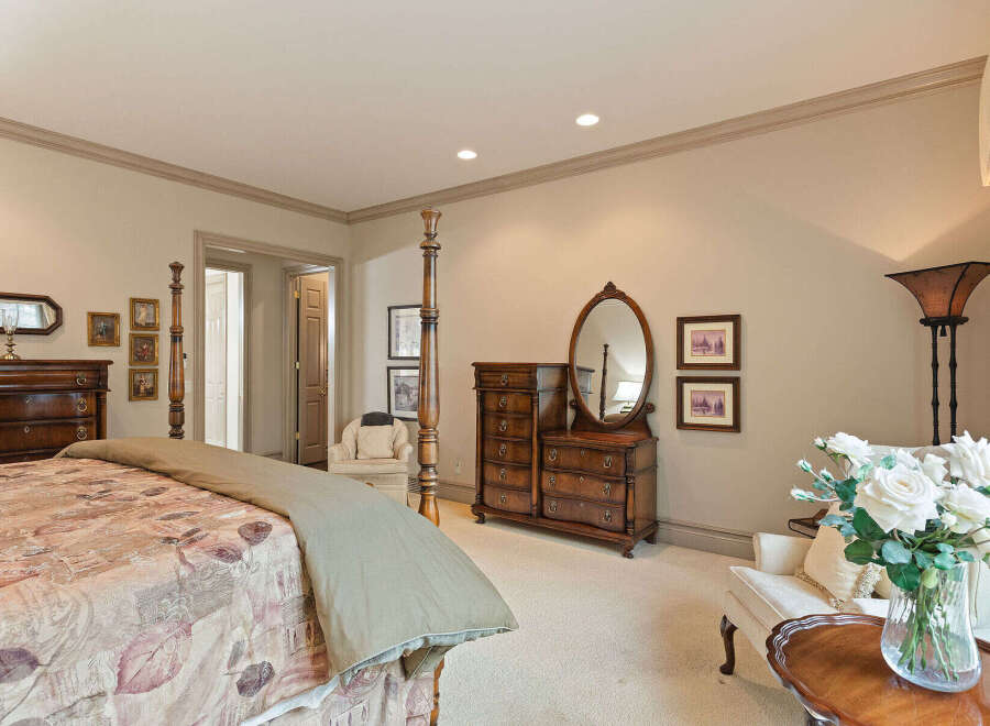 This elegant bedroom features a luxurious four-poster bed with a patterned comforter and a neutral throw.