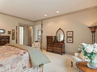 This elegant bedroom features a luxurious four-poster bed with a patterned comforter and a neutral throw.
