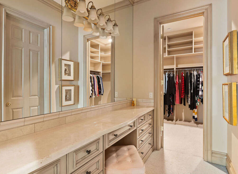 Step into this elegant dressing room, featuring a spacious vanity with ample storage and a plush stool, perfect for your morning routine.