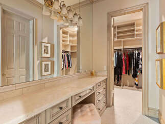 Step into this elegant dressing room, featuring a spacious vanity with ample storage and a plush stool, perfect for your morning routine.