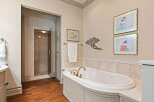 Indulge in luxury in this elegant bathroom featuring a spacious soaking tub with elegant gold fixtures.
