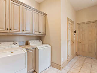 This laundry room offers ample storage with a full wall of light wood cabinets above the washer and dryer.