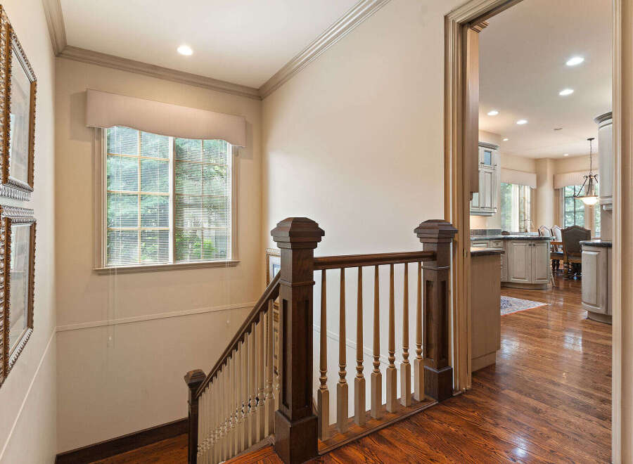 This stunning home features a beautifully crafted staircase with rich wooden banisters and spindles, leading to an open-concept living space.