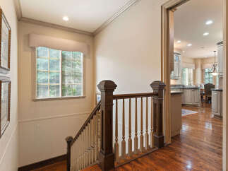 This stunning home features a beautifully crafted staircase with rich wooden banisters and spindles, leading to an open-concept living space.
