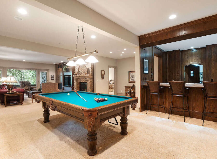 This finished basement offers the ultimate entertainment space, featuring a full-size pool table and a custom-built wood bar with ample seating.