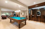 This finished basement offers the ultimate entertainment space, featuring a full-size pool table and a custom-built wood bar with ample seating.