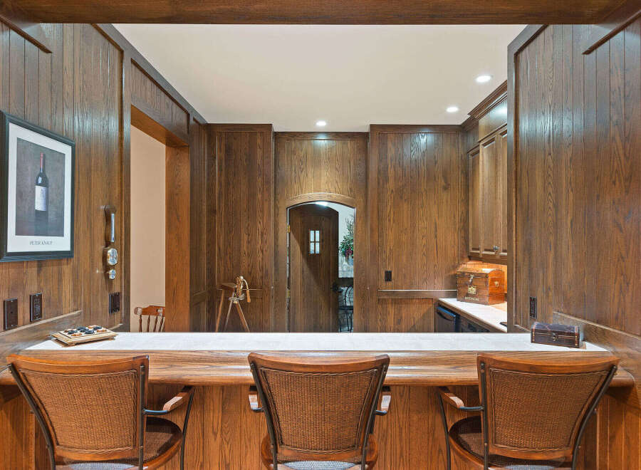 Step into this beautifully appointed home bar, featuring rich wood paneling and a spacious counter perfect for entertaining.